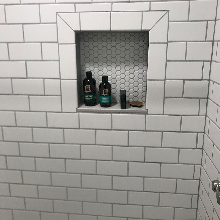 White subway tile shower with a built-in niche by Sparrow Contracting