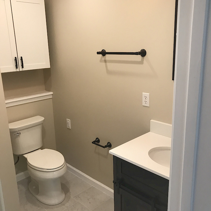 Updated bathroom with a charcoal vanity, quartz countertop, white shaker storage cabinet, and oil-rubbed bronze fixtures.