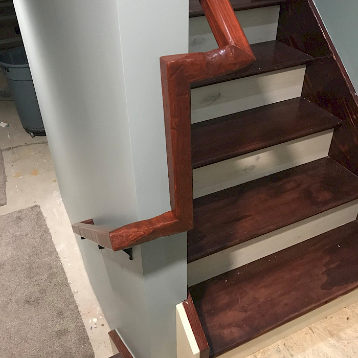 Stained wood stair treads and handrail installed by Sparrow Contracting